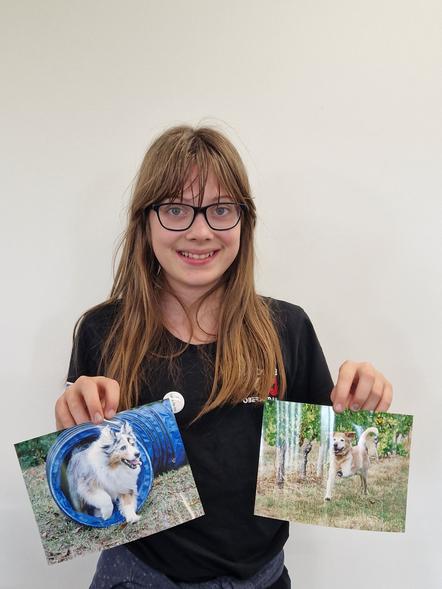 Laura zeigt stolz zwei Hundefotos